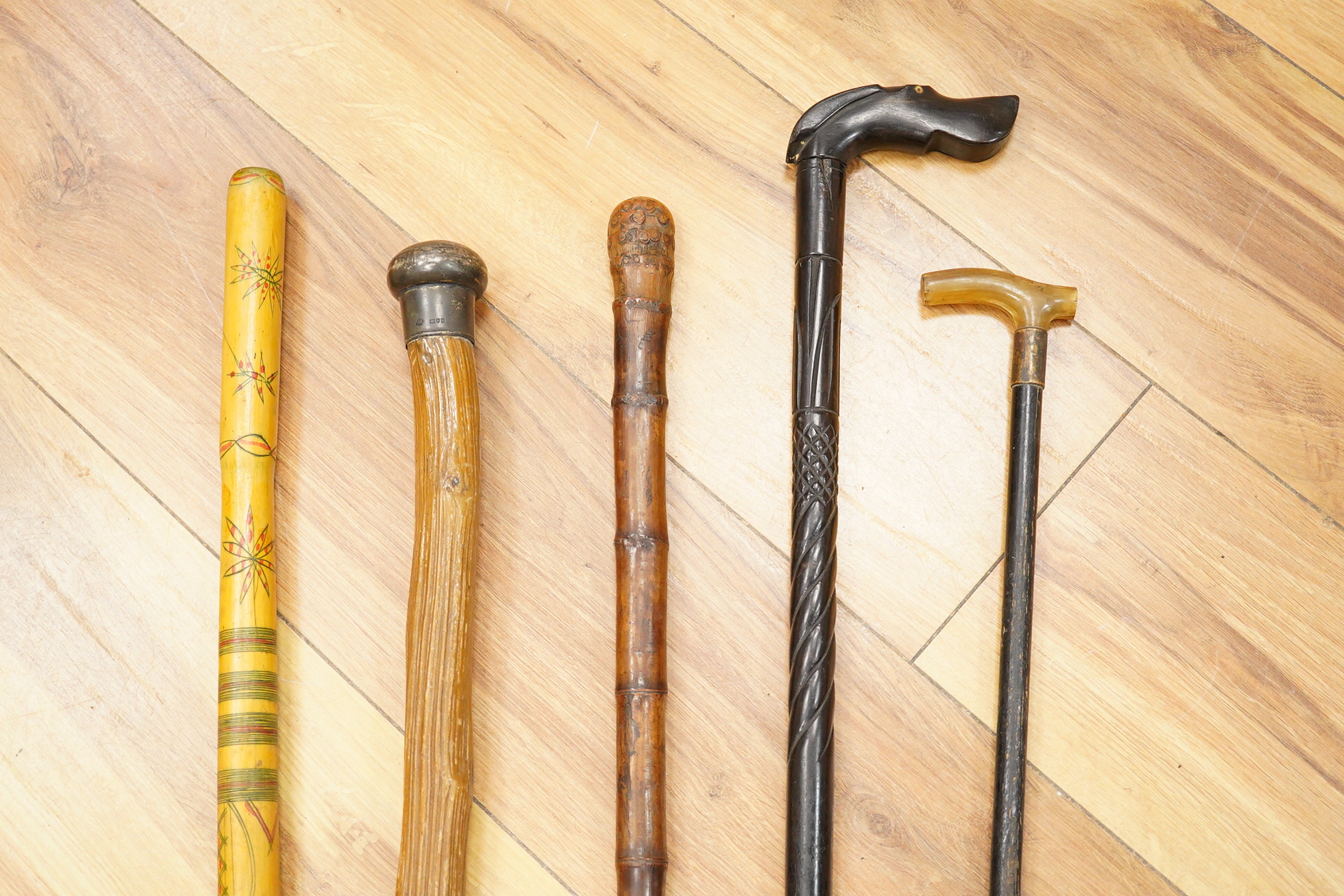 Five walking sticks including horn and a silver topped walking sticks and a carved topped walking stick with concealed chamber containing a metal tube - 93cm long. (5).